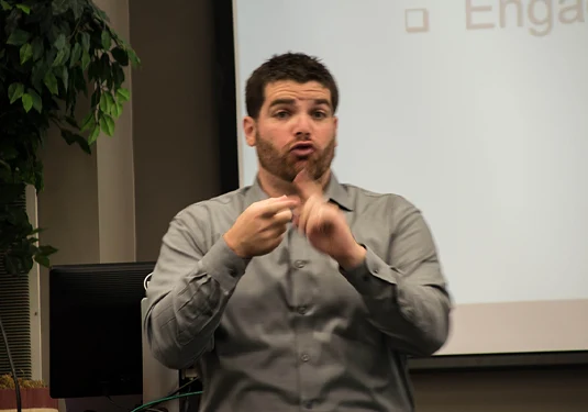 Corey Axelrod signing during a presentation.