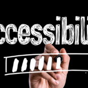 A hand is writing the word "accessibility" in white chalk-like letters on a black background. Below the word, the hand is drawing a loading bar, which is about one-third filled with white segments.