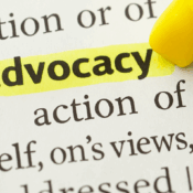 A close-up image of a dictionary page with the word “self-advocacy” prominently highlighted in bright yellow. The highlighting is being applied by a yellow marker with a pointed tip visible in the top right corner of the image. The surrounding text provides part of the definition, including words like "action of represent" and "oneself, one's views." The focus is on emphasizing the importance of self-advocacy.