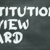 The image shows a dark, textured background, resembling a chalkboard. The words "INSTITUTIONAL REVIEW BOARD" are written on it. The letters "IRB" are stacked vertically on the left side and are colored in a vibrant red, while the rest of the words "INSTITUTIONAL," "REVIEW," and "BOARD" are written horizontally in white, aligned with each of the red letters. The white letters have a chalk-like texture.