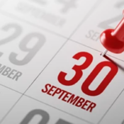 A close-up of a calendar page showing the date September 30 marked in red text with a red pushpin inserted above it.