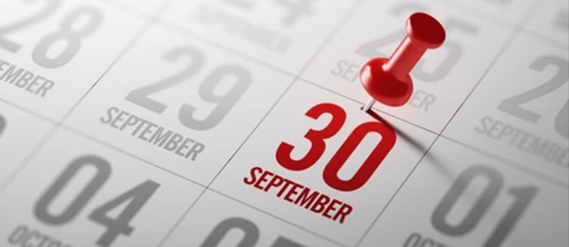 A close-up of a calendar page showing the date September 30 marked in red text with a red pushpin inserted above it.